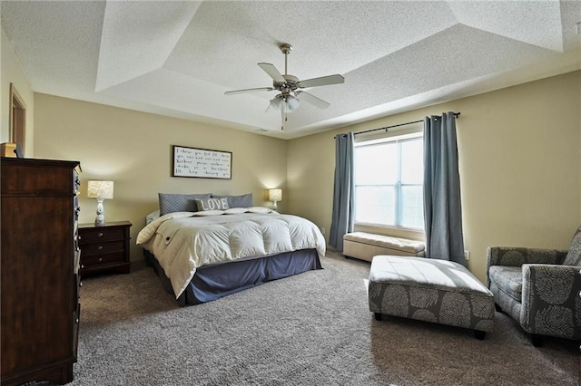 carpeted bedroom featuring ceiling fan, a tray ceiling, and a textured ceiling