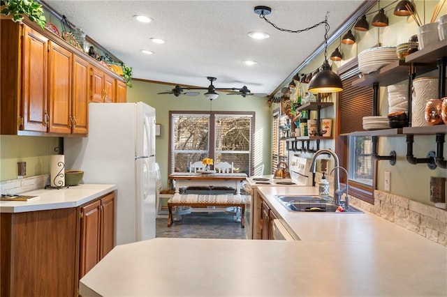 kitchen with sink, a textured ceiling, kitchen peninsula, pendant lighting, and white appliances