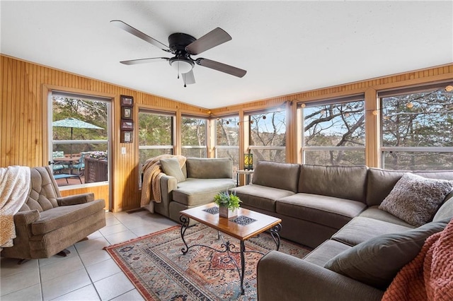 living room featuring light tile patterned floors, a wealth of natural light, wooden walls, and ceiling fan