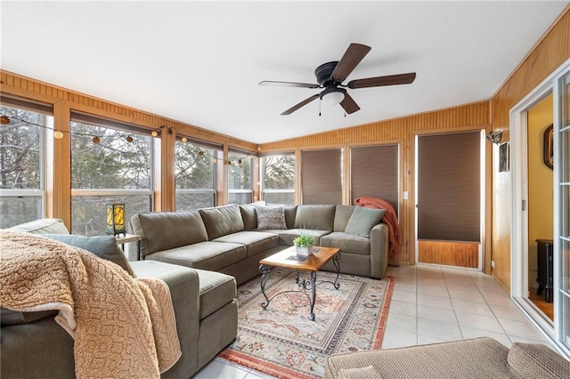 living room with ceiling fan, light tile patterned floors, and wooden walls