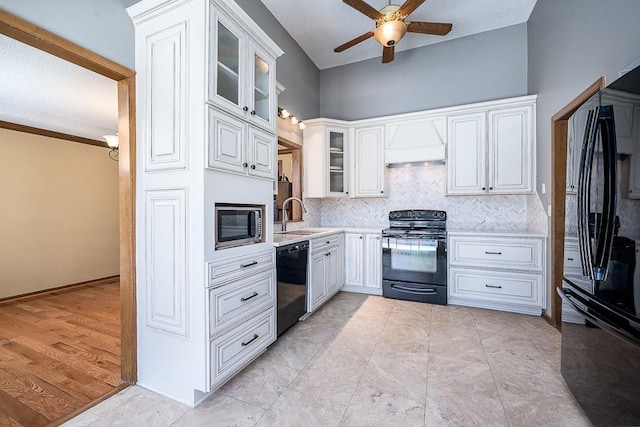 kitchen with sink, backsplash, black appliances, custom range hood, and white cabinets