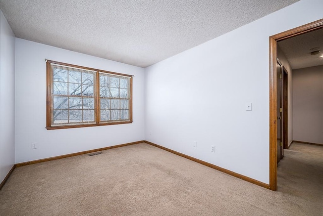 unfurnished room featuring light colored carpet and a textured ceiling