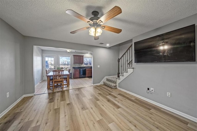 unfurnished living room featuring ceiling fan, a textured ceiling, and light hardwood / wood-style flooring