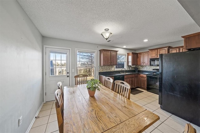 dining space with sink, light tile patterned floors, and a textured ceiling