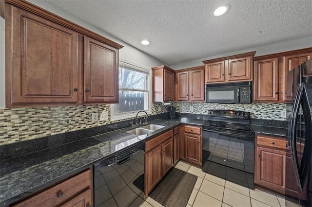 kitchen featuring sink, tasteful backsplash, light tile patterned floors, dark stone counters, and black appliances