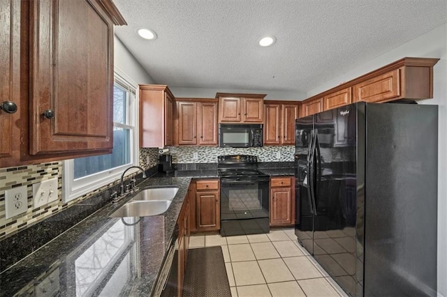 kitchen featuring sink, black appliances, light tile patterned floors, dark stone counters, and backsplash