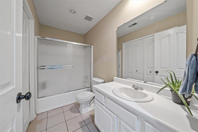 full bathroom with toilet, bath / shower combo with glass door, a textured ceiling, vanity, and tile patterned flooring