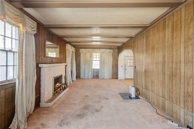 unfurnished living room with carpet, a fireplace, and wood walls