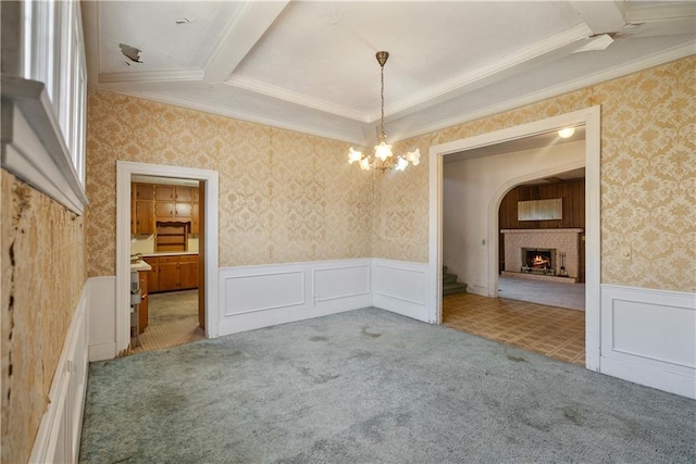 unfurnished dining area featuring a brick fireplace, carpet, and a notable chandelier