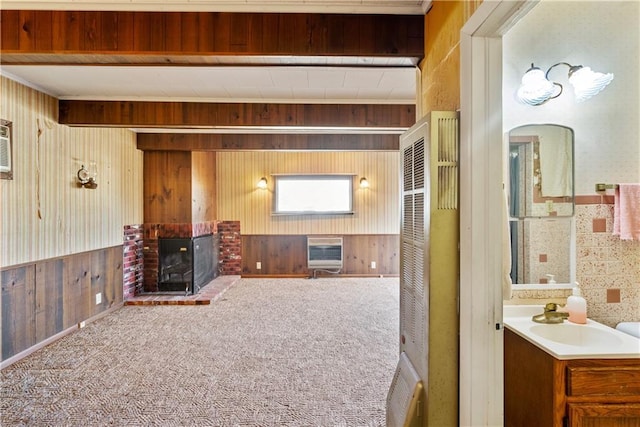 carpeted living room featuring sink, heating unit, a fireplace, and wooden walls