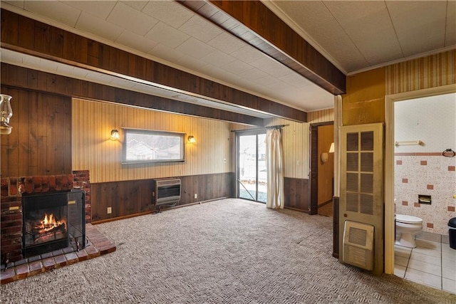 carpeted living room with crown molding, a brick fireplace, heating unit, and wooden walls