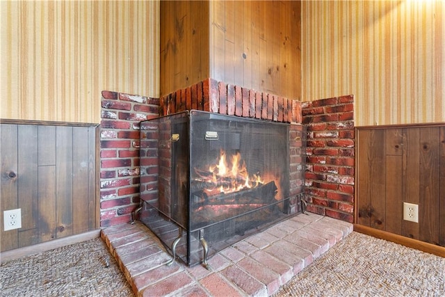 details with a brick fireplace, carpet floors, and wood walls