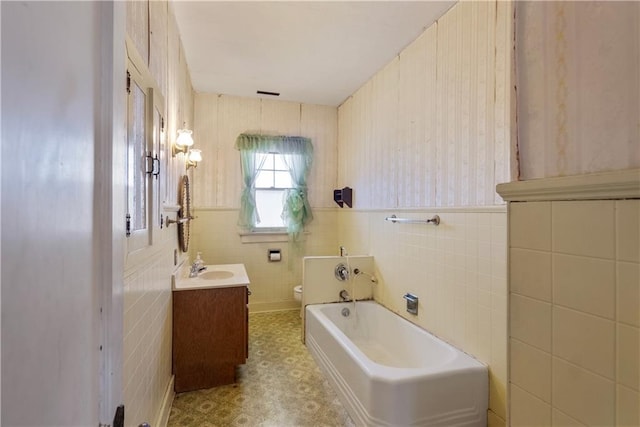 bathroom with vanity, toilet, a bath, and tile walls