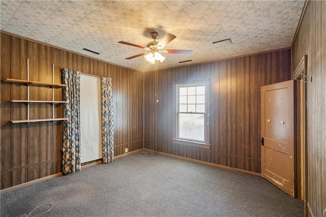 unfurnished room with ceiling fan, carpet floors, and wood walls