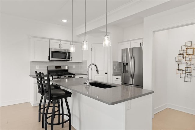 kitchen with sink, white cabinetry, stainless steel appliances, decorative light fixtures, and dark stone counters