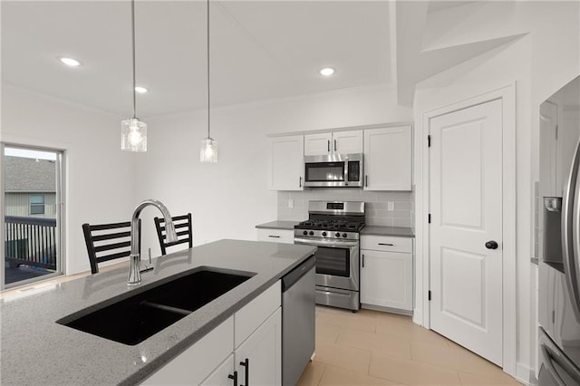 kitchen featuring sink, appliances with stainless steel finishes, hanging light fixtures, white cabinets, and dark stone counters