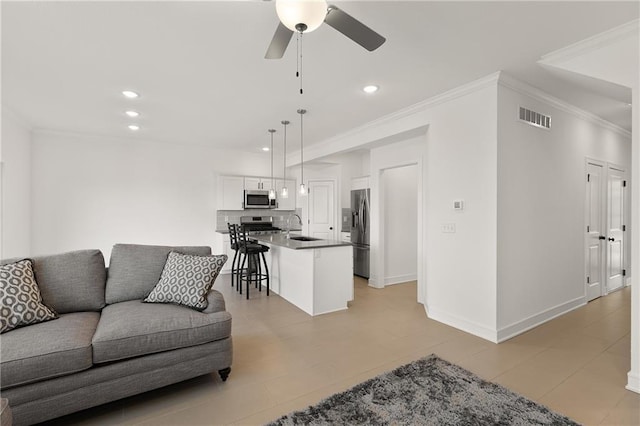 living room featuring sink, ornamental molding, and ceiling fan