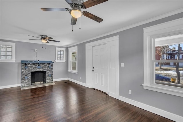 unfurnished living room featuring ceiling fan, ornamental molding, a stone fireplace, and dark hardwood / wood-style flooring