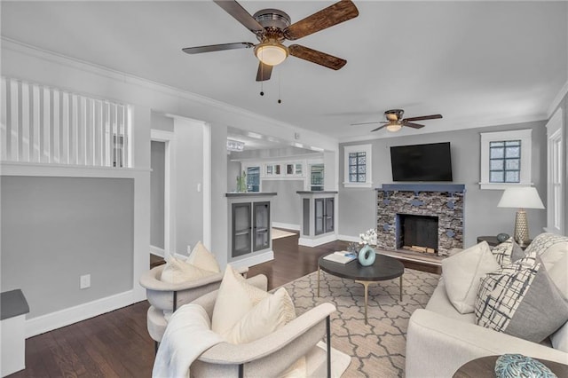 living room featuring dark wood-type flooring, ceiling fan, a fireplace, and crown molding