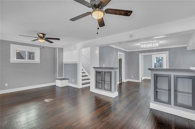 unfurnished living room with dark wood-type flooring, ceiling fan, ornamental molding, and a wealth of natural light