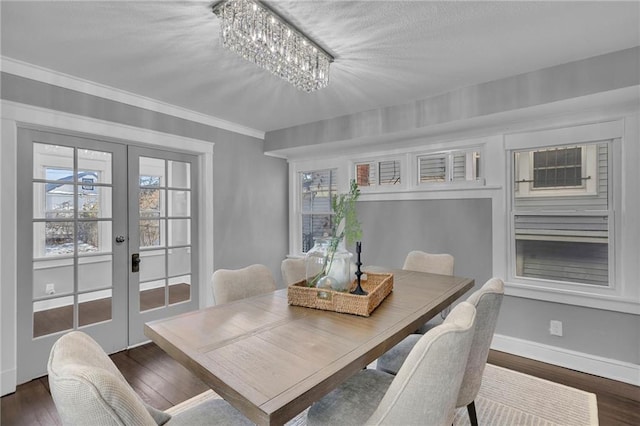 dining room with french doors, dark hardwood / wood-style floors, crown molding, and a notable chandelier