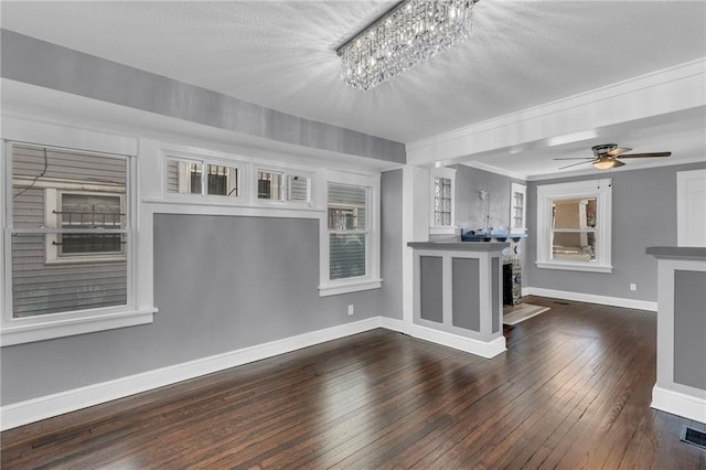 unfurnished living room featuring ceiling fan with notable chandelier and dark hardwood / wood-style floors