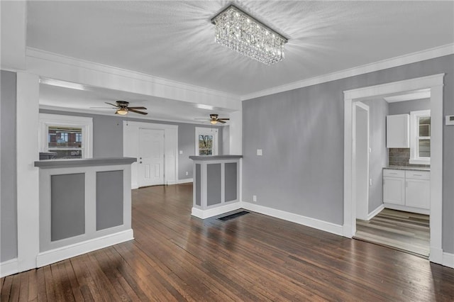 unfurnished living room with an inviting chandelier, crown molding, and dark wood-type flooring