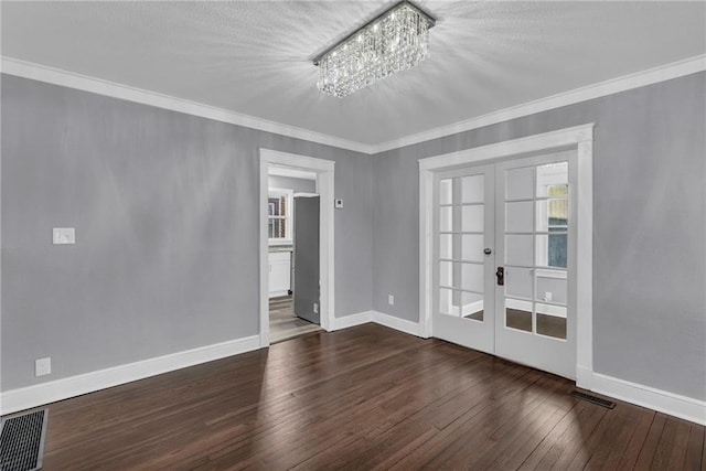 spare room with an inviting chandelier, dark wood-type flooring, ornamental molding, and french doors