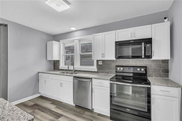 kitchen with backsplash, white cabinets, sink, and black appliances