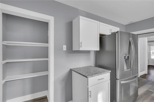 kitchen featuring white cabinetry, dark hardwood / wood-style floors, light stone counters, and stainless steel fridge with ice dispenser