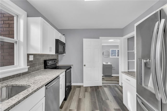 kitchen with dark wood-type flooring, appliances with stainless steel finishes, light stone counters, white cabinets, and decorative backsplash