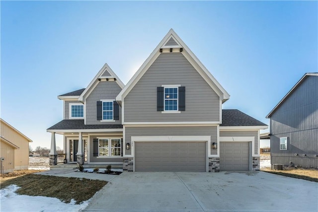 view of front of home with a garage, central AC unit, and covered porch