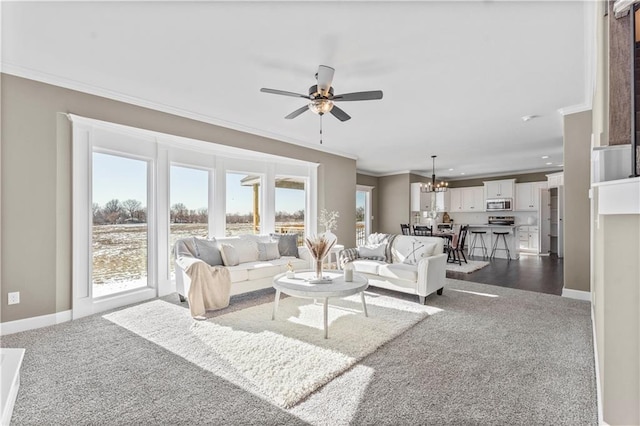 carpeted living room featuring crown molding and ceiling fan with notable chandelier