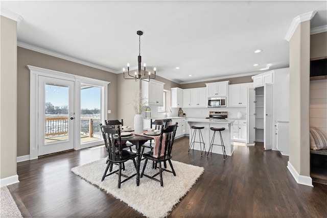 dining space featuring sink, crown molding, dark wood-type flooring, and a chandelier