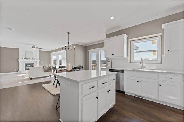 kitchen featuring dishwasher, hanging light fixtures, a large fireplace, white cabinets, and a kitchen island