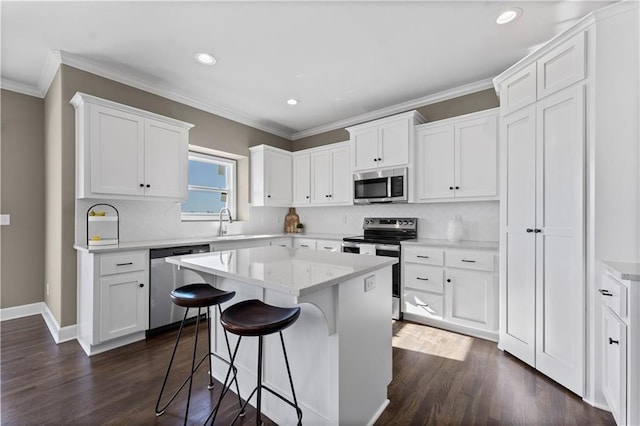 kitchen featuring a breakfast bar area, appliances with stainless steel finishes, dark hardwood / wood-style floors, a center island, and white cabinets