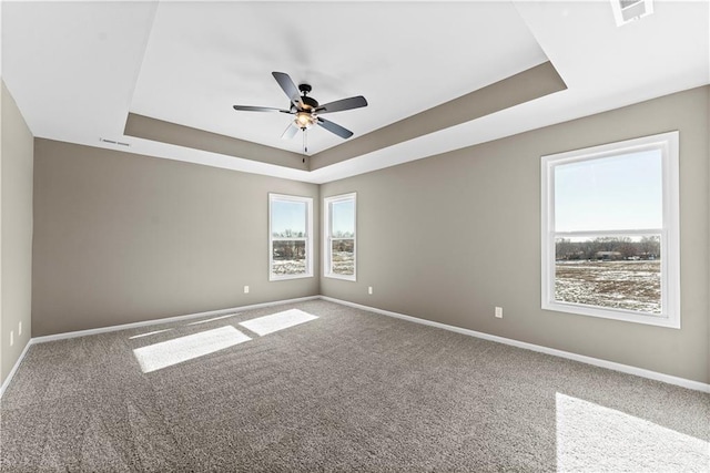 unfurnished room with a raised ceiling, ceiling fan, and carpet flooring