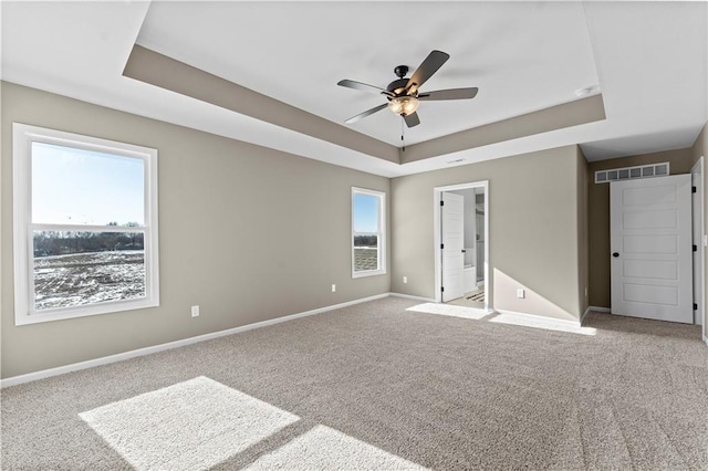 unfurnished bedroom featuring light carpet, a raised ceiling, ceiling fan, and ensuite bathroom