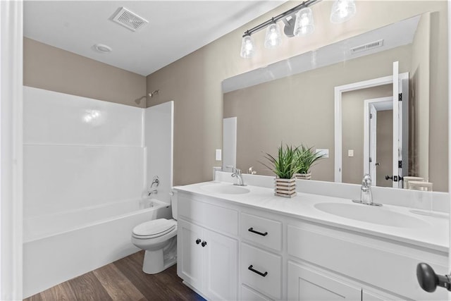 full bathroom with hardwood / wood-style flooring, shower / tub combination, vanity, and toilet