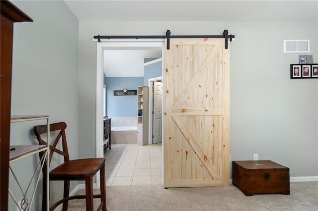 corridor featuring a barn door and light carpet