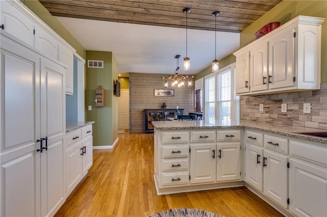 kitchen featuring decorative light fixtures, wooden ceiling, kitchen peninsula, white cabinets, and backsplash