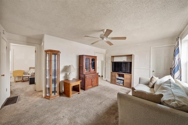 living room with a textured ceiling, light colored carpet, and ceiling fan