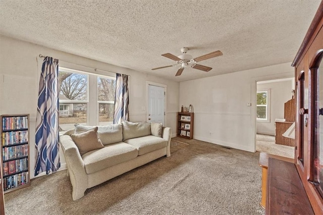 living room with ceiling fan, carpet, and a textured ceiling