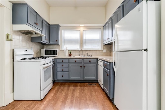 kitchen with tasteful backsplash, sink, white appliances, and light hardwood / wood-style floors