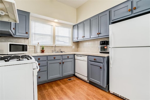 kitchen featuring sink, tasteful backsplash, gray cabinets, white appliances, and light hardwood / wood-style floors