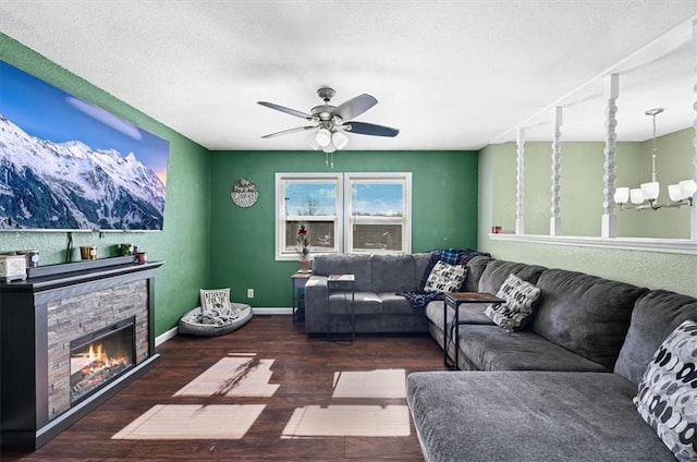 living room featuring dark wood-type flooring, a fireplace, ceiling fan with notable chandelier, and a textured ceiling