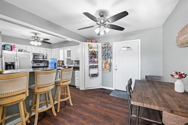 kitchen with appliances with stainless steel finishes, dark hardwood / wood-style floors, kitchen peninsula, ceiling fan, and white cabinets