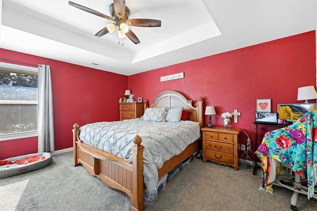 bedroom featuring ceiling fan, carpet flooring, and a raised ceiling