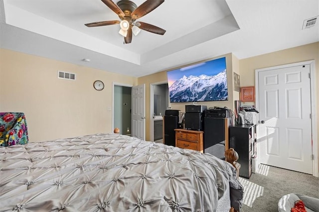 carpeted bedroom featuring a raised ceiling and ceiling fan