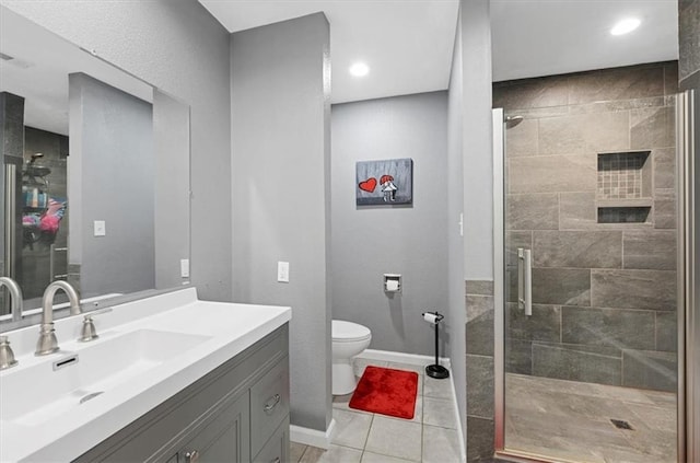 bathroom featuring tile patterned floors, vanity, toilet, and a shower with shower door